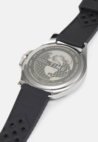 Reloj Timex con caja de acero inoxidable, correa de goma negra y diseño grabado de un globo plateado en la parte posterior, con resistencia al agua WR 100m.