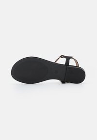Sandalo nero con tomaia liscia, cinturino alla caviglia regolabile e suola in gomma piatta e testurizzata. Design minimalista senza decorazioni visibili.