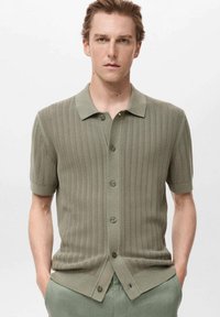 Kurzärmliges gestricktes Poloshirt in gedämpftem Grün, mit einem strukturierten Rippmuster, einer Brusttasche und einer Knopfleiste auf der Vorderseite.