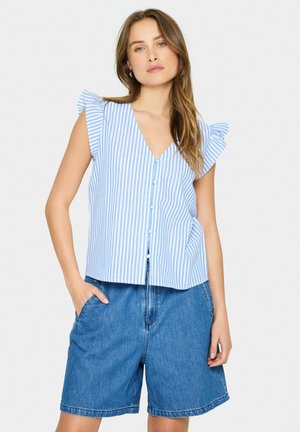 Blå og hvid stribet ærmeløs top med V-hals og flæser på skuldrene, parret med denim shorts. Knapper ned foran.