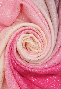 Tessuto brillante in sfumature di rosa, caratterizzato da una consistenza morbida e da puntini dorati, arrotolato in una formazione circolare.