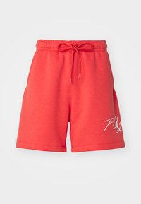 Shorts rouges à taille élastique avec cordon et logo en écriture blanche sur la jambe gauche, affichés sur fond uni.