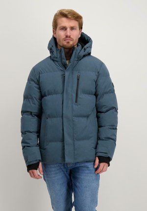 Gevoerde teal jas met hoge kraag en capuchon. Voorzien van een ritszak op de borst, elastische manchetten en een getailleerde zoom. Gedeeltelijk over een jeans gedragen.