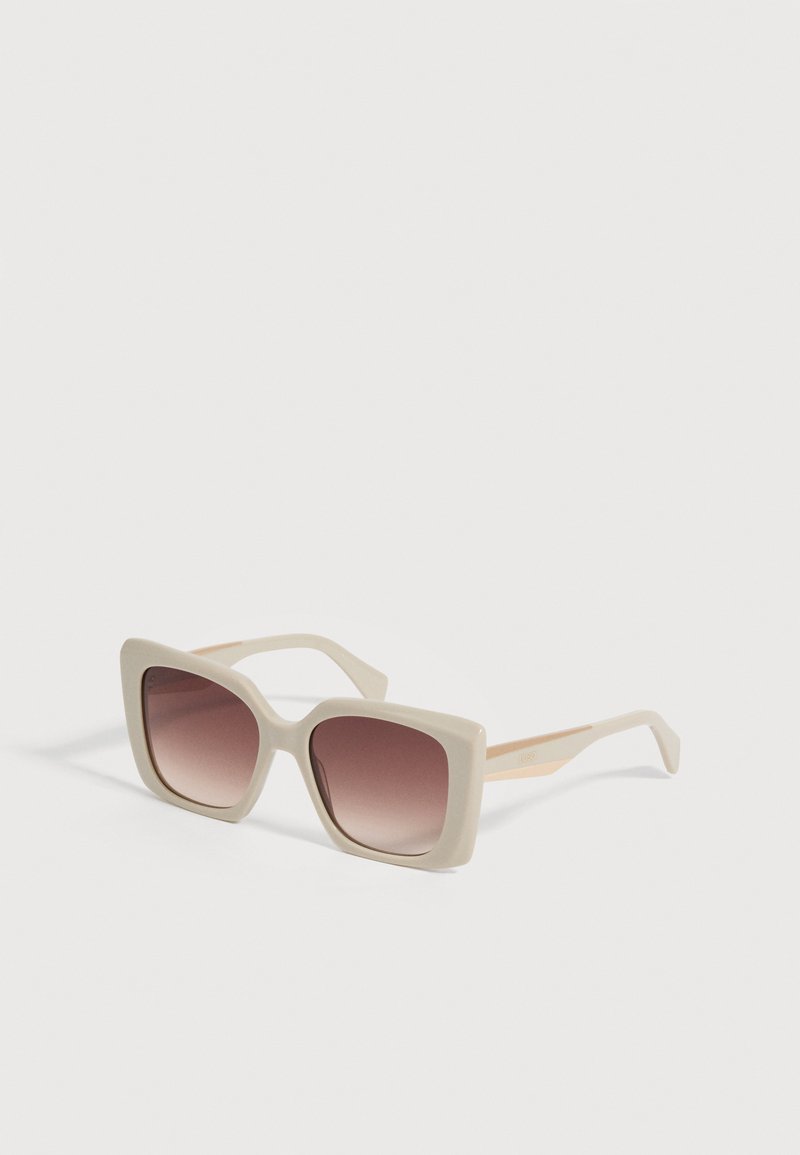 Lunettes de soleil carrées oversized couleur crème avec verres marron dégradés sur fond blanc.