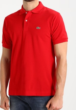 Polo en coton rouge avec un col classique, des manches courtes et un logo crocodile vert sur la poitrine gauche. Design simple et ajusté.