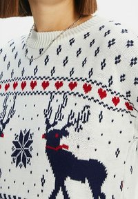 Stickad vit tröja med ett marinblått ren-design, röda hjärtan och snöflingor. Ribbat hals- och ärmdetalj med texturerat tyg.