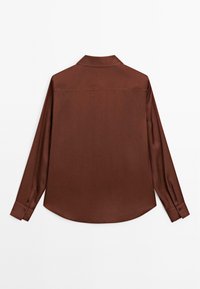 Chemise marron à manches longues avec col, présentant une texture lisse et des poignets boutonnés. L'arrière affiche un design simple et épuré.