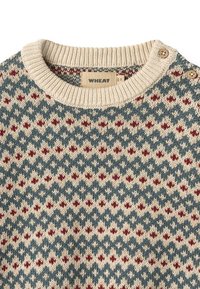 Maglione a maglia crema con un motivo geometrico nelle tonalità di blu e rosso. Presenta un colletto a coste e due bottoni in legno sulla spalla.