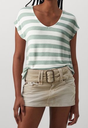 T-shirt à manches courtes rayé vert et blanc avec un col en V, associé à une jupe mini en velours côtelé beige avec une large ceinture.
