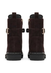 Botas de tobillo de ante marrón con un acabado texturizado, cremalleras laterales y acentos en tono dorado. Suelas de goma negra gruesa.