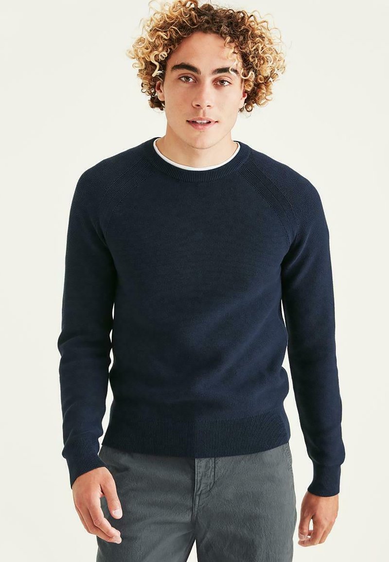 Pull en tricot bleu marine avec un col rond, des manches raglan texturées et des bords-côtes aux manches et à l'ourlet. Matière lisse et coupe ajustée.