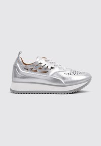 Zapatilla metálica plateada con diseño perforado, suela de goma blanca y cierre de cordones en la parte delantera. Presenta acentos troquelados en los laterales para ventilación.