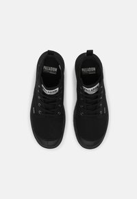 Černé vysoké tenisky vyrobené z plátna, s černými tkaničkami, gumovými špičkami a logem na jazyku. Hladký povrch s minimálními akcenty.