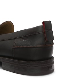 Brauner Lederschuh mit abgerundetem Rücken, kontrastierender Naht und Gummisohle mit strukturierten Mustern. Enthält ein kleines rotes Akzentetikett.