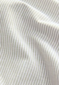 Tissu beige et blanc à rayures verticales avec de légères plis et un motif de tissage texturé.