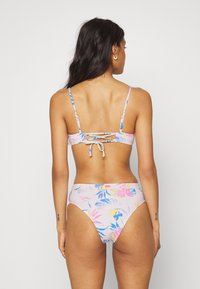 Conjunto de biquíni floral em rosa pastel, com alças ajustáveis, detalhe nas costas amarrado e parte de baixo de cintura alta com padrões vibrantes em azul e amarelo.