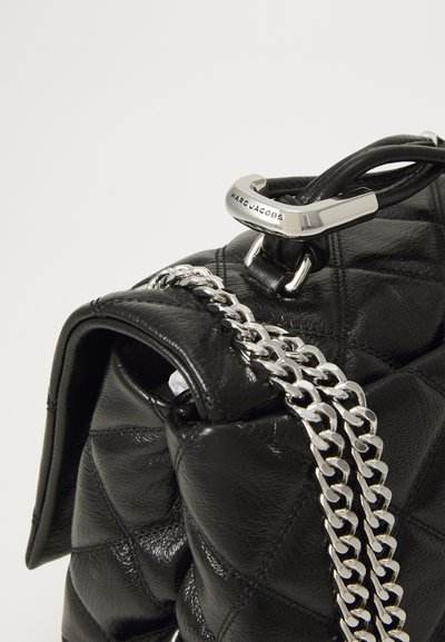Borsa a tracolla nera in pelle trapuntata con catena argentata, caratterizzata da un accentuato dettaglio in metallo argentato con la scritta "MARC JACOBS" incisa.