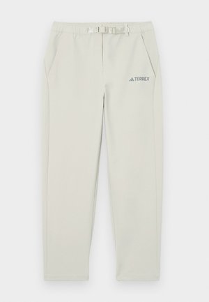 Pantaloni atletici gri deschis, cu un tiv elastic, detaliu cu brâu, două buzunare laterale și un mic logo albastru "TERREX" pe coapsa stângă.