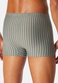 Türkisfarbene Boxershorts mit dünnen braunen Streifen. Aus weichem Stoff gefertigt, mit einem dehnbaren Bund und einer figurbetonten Passform.