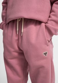 Roze katoenen joggingsbroek met een trekkoord, voorzien van een bijlogo op de zak en geribbelde boorden. Soepele textuur en een relaxte pasvorm.
