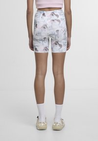 Väljerryttävät shortsit korkealla vyötäröllä, joissa on vaaleanvärinen marmori-kuvio. Materiaali on sileä ja joustava. Valkoiset, joissa on vaaleanpunaisia, harmaita ja sinisiä sävyjä.