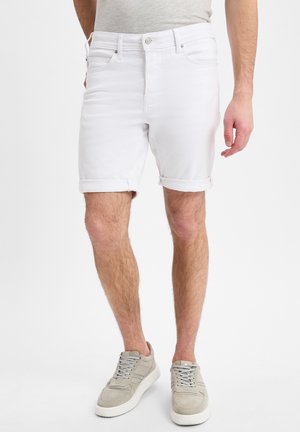 Witte katoenen denim shorts met opgerolde boorden, voorzien van vijf zakken en zilveren knoopdetails, gedragen met lichtgrijze sportschoenen.