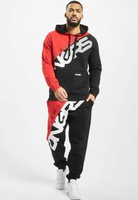 Hooded sweatshirt and joggers set in red and black. Features bold white graphics, contrasting panels, and ribbed cuffs. Cotton blend material.