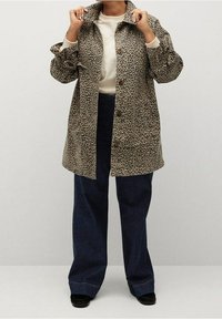 Cappotto con stampa leopardata, colletto, chiusura a bottoni e due tasche laterali. Abbinato a jeans larghi scuri e scarpe nere.