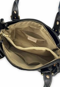 Sac à main en cuir noir avec fermeture éclair. Intérieur doublé de tissu beige, comprenant plusieurs poches et un compartiment sécurisé avec fermeture éclair.