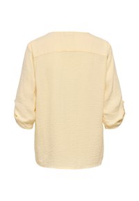 Lichtgele, loszittende blouse met driekwart mouwen en een gestructureerde stof. Heeft een eenvoudig ontwerp aan de achterkant en een ronde halslijn.