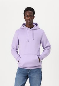 Purple hoodie made of soft fabric, featuring a kangaroo pocket, drawstring hood, and ribbed cuffs. Paired with blue jeans.