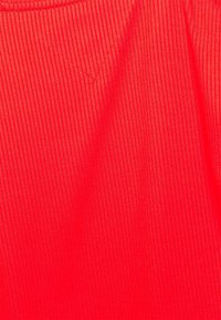 Tejido acanalado de color rojo brillante con sutiles líneas verticales y una costura en forma de V cerca del centro superior.