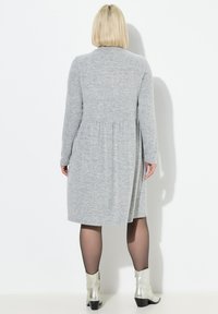 Robe grise à manches longues en tissu texturé, taille plissée et ourlet au genou. Portez-la avec des bottines argentées.
