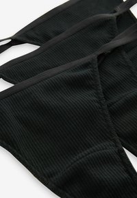 Perizoma nero a costine con sottili fasce elastiche, dotato di bordi senza cuciture e di un tessuto testurizzato per il comfort.