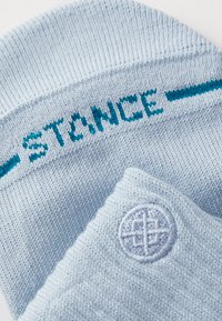 Világoskék zoknik, turquoise színű "STANCE" felirattal és kör alakú hímzett logóval. Puha, textúrált anyagból készült, bordázott felső résszel.