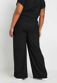 Mustat leveälahkeiset housut, joissa on teksturoitu pinta. Pehmeä kangas, rento malli, joustava vyötärö ja sileä helma. Sopii arkikäyttöön.