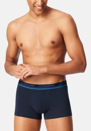 Navy blue boxer briefs made of soft fabric, featuring an elastic waistband with "uncover" logo in blue. The design is fitted and seamless.