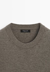 Šedý pletený svetr s kulatým výstřihem, s ribovaný límcem a štítkem s nápisem "Massimo Dutti". Měkká textura a jemný design.