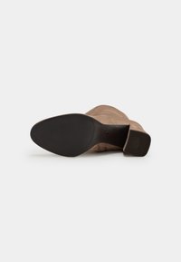 Brown suede ankle boot with a rounded toe, textured black rubber sole, and a low block heel. Smooth upper with subtle stitching details.