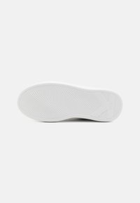 Suela de zapatilla blanca con un patrón de olas texturizado, que cuenta con un logotipo prominente y bordes redondeados. El material parece ser ruborizado y flexible.