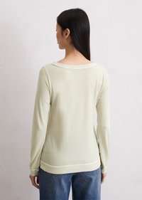 Lys grønn, langermet strikkegenser med båt-utrigning og ribbestrikkede mansjetter. Myk tekstur med en avslappet passform, kombinert med høyt liv jeans.