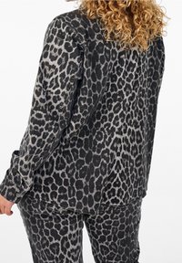 Schwarze und graue Leopardenmuster-Jacke aus Denim, mit Knopfverschluss, langen Ärmeln und einer leicht strukturierten Oberfläche.