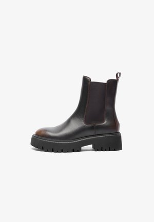 Botas de tobillo de cuero marrón con paneles laterales elásticos, suela de goma negra gruesa, punta redondeada, costura en contraste y tirador en la parte posterior.
