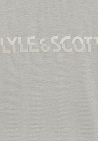 Grå bomulds-t-shirt med brandnavnet "LYLE & SCOTT" i en tekstureret, fed print henover fronten. Blødt stof, afslappet design.
