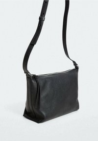 Borsa a spalla in pelle nera con forma rettangolare, texture liscia, chiusura con zip e tracolla regolabile. Presenta dettagli di design minimal.