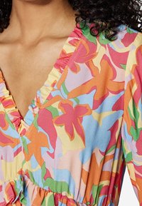 Robe multicolore en tissu léger avec un motif floral, décolleté en V froncé et taille élastiquée pour un ajustement décontracté.