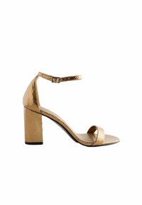 Arany sarkú szandál, textúrált kígyómintás dizájnnal, bokapánttal, nyitott orral és stabil blokk sarkal. Simább belső talp.