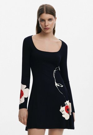 Robe côtelée bleu marine à manches longues avec des motifs floraux rouges et blancs sur les manches, et un décolleté carré. Texture lisse.