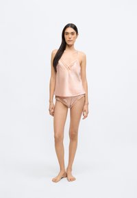 Siidist pidžaamalik komplekt pehmes roosas toonis, millel on pitsdetailid särgi ja lühikeste pükste peal, õhukeste rihmade ja lõdva lõikega. Ühtlane siidine tekstuur.