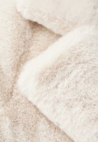 Tessuto morbido in pelliccia sintetica di colore crema beige con una texture soffice, caratterizzato da sottili variazioni di tono e una superficie liscia e accogliente.